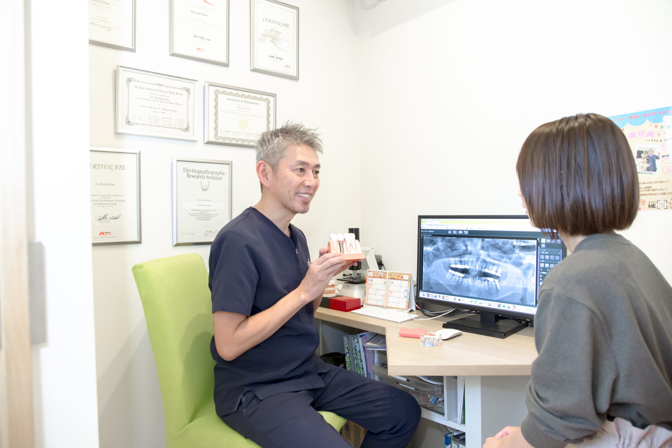 歯科医師が40〜60代の患者にインプラント治療の説明をしている様子。