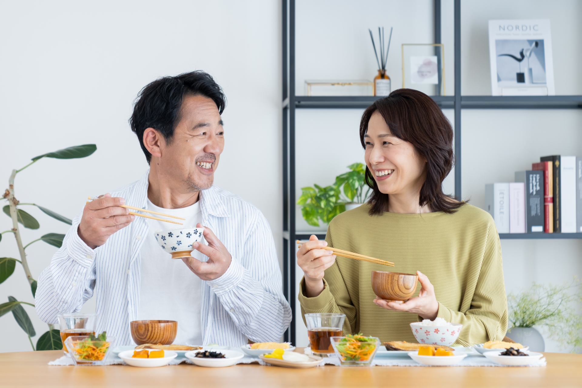 40〜60代の男女が食事を楽しむ様子。インプラントで噛める喜びを表現したイメージ写真。